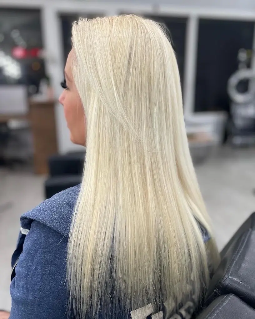 A woman with long blonde hair extensions, smiling and showing off her new look.
