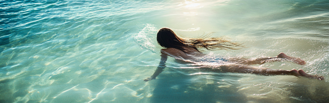 Sew in Hair Extensions 8 Seamlessly blended hair extensions on a woman swimming in clear ocean water.