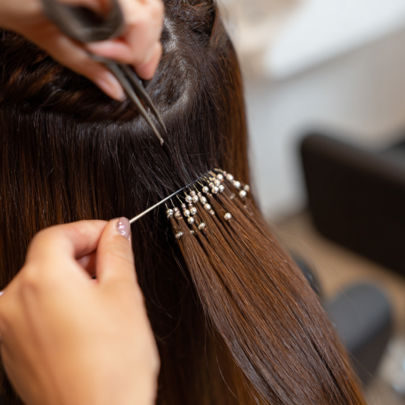 Close-up of professional installing I-tip hair extensions with microbeads.