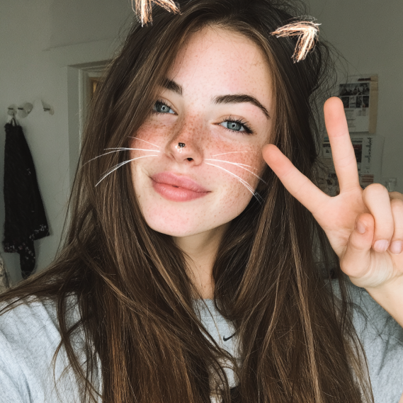 A woman with shoulder-length curly hair, showing the volume added by tape-in hair extensions.